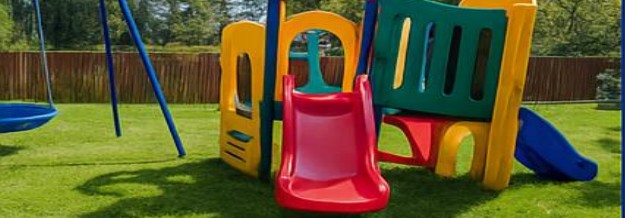 Outdoor play area with slide and nest swing on a green lawn